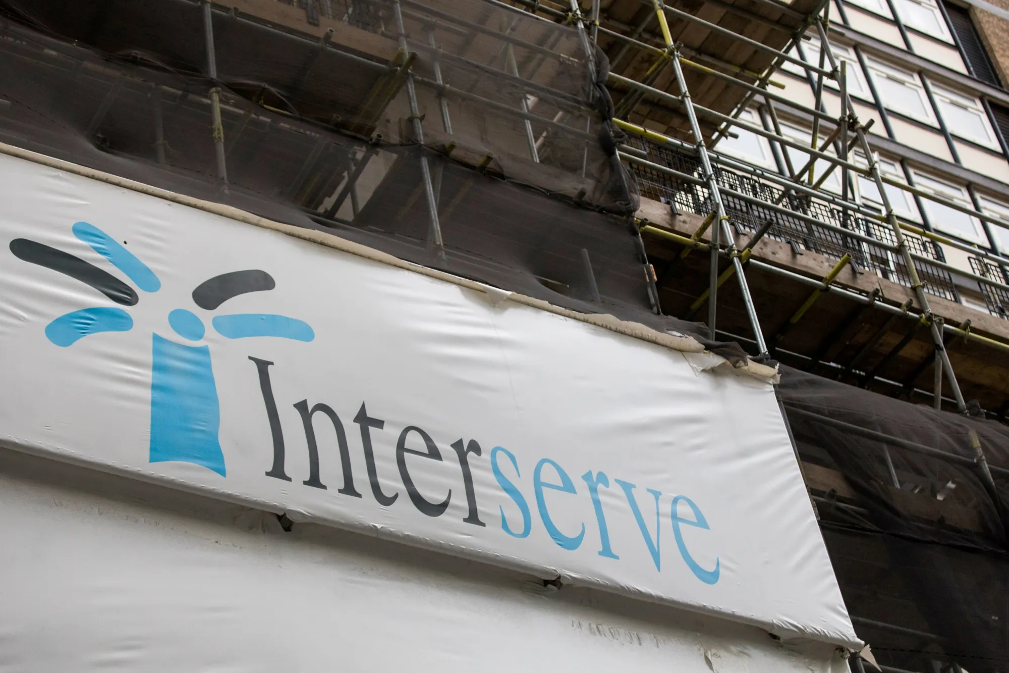 The Interserve logo sits on a hoarding at a construction site.