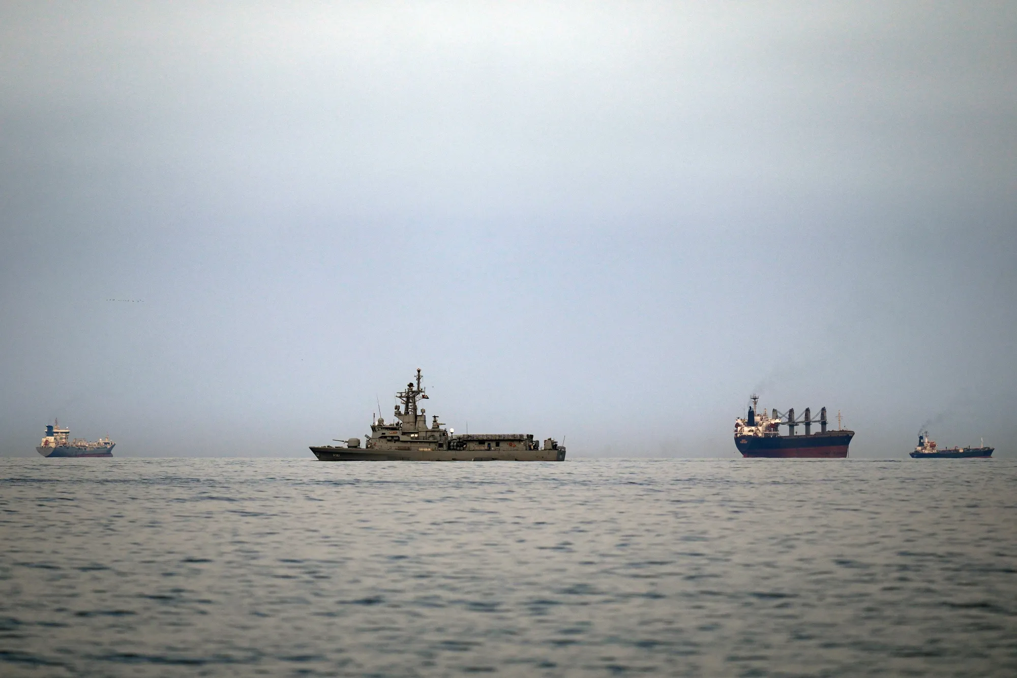 A UAE navy vessel patrols next to cargo ships and oil tankers in the Strait of Hormuz last week. (AP Photo/Altaf Qadri)