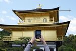 A tourist uses a smartphone to take a photo of the Kinkakuji temple.