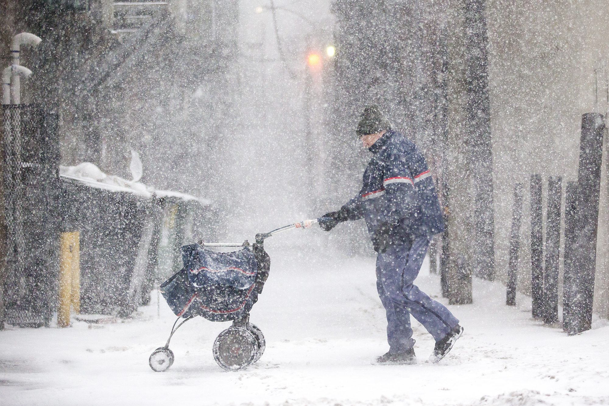 A United States Postal Service letter carrier delivers mail during a snow storm.