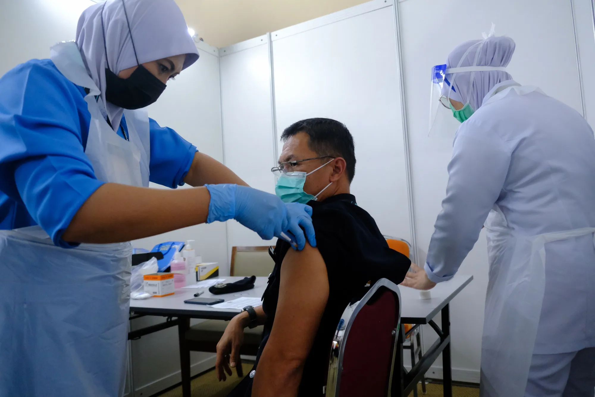 A healthcare worker administers a dose of the Pfizer-BioNTech Covid-19 vaccine to a frontline worker at the Malaysia Agro Exposition Park Serdang (MAEPS) vaccination center in Serdang, Selangor, Malaysia, on Thursday, March 4, 2021. The first phase of the vaccine roll-out that will run through April involves about 500,000 frontliners comprising health-care, defense and security personnel, as well as teachers with co-morbidities, according to the government.