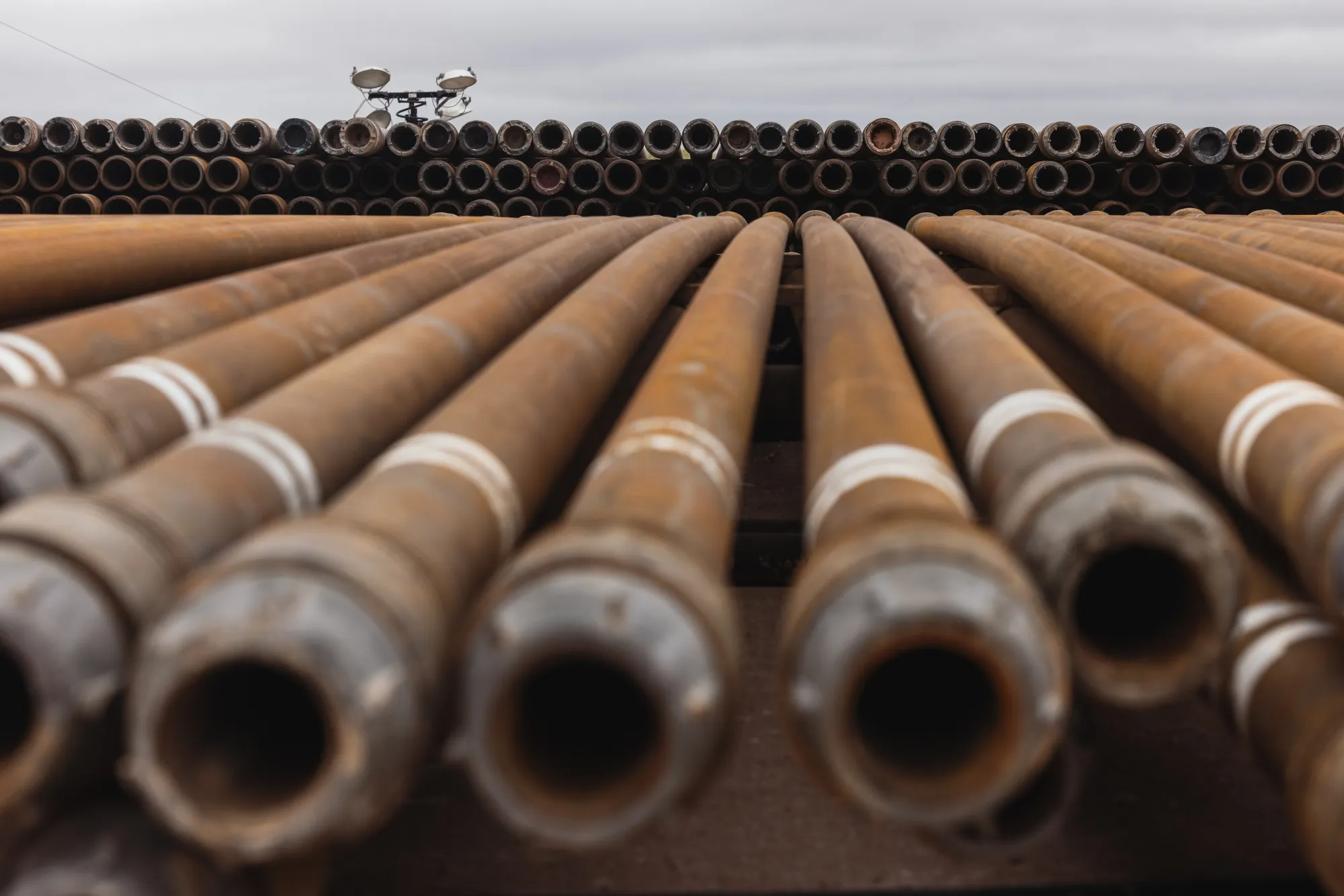 Stacks of steel pipes used for drilling oil wells at a drilling site on the land that the University of Texas System overseas in Andrews, Texas, US, on Thursday, June 2, 2022. Every day, the University of Texas System makes about $6 million off a mineral-rich swath of land it manages in the US’s largest oil field.