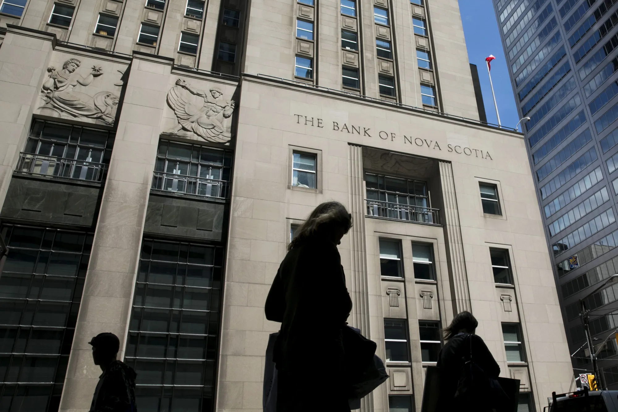 Pedestrians walk past the Bank of Nova Scotia building in Toronto.