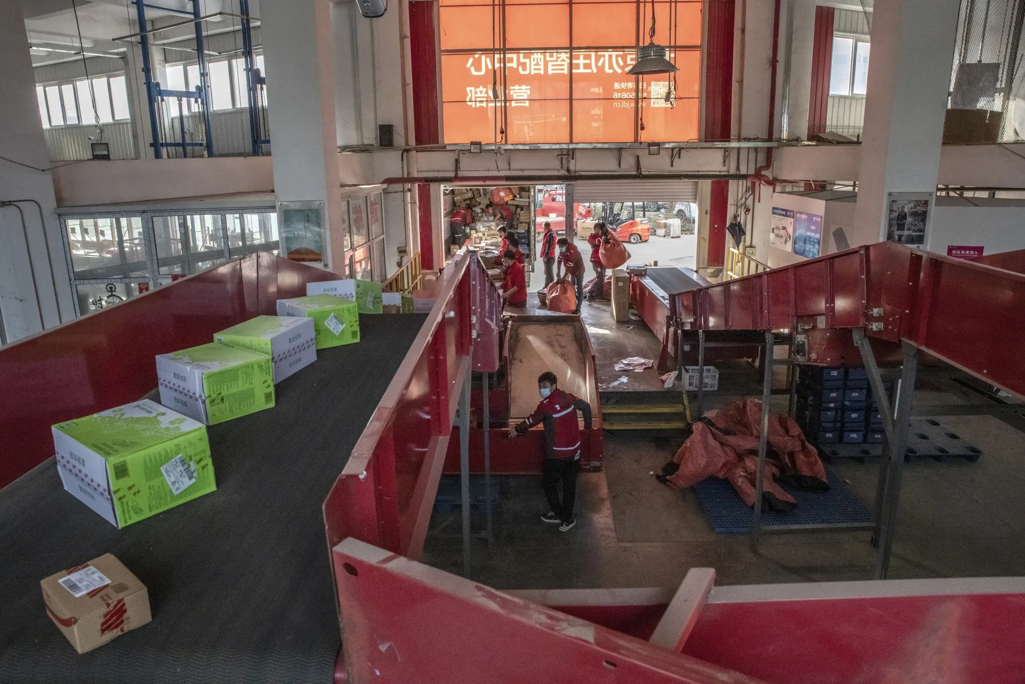 Workers unload parcels onto a conveyor belt at a JD.com sorting center in Beijing.