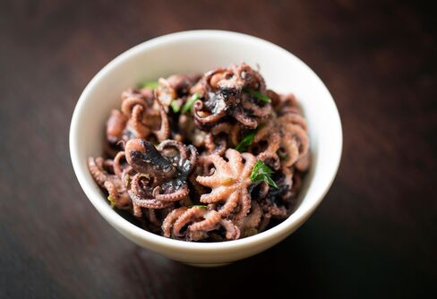A starter of baby octopus comes in a bowl with red pepper and cucumber.