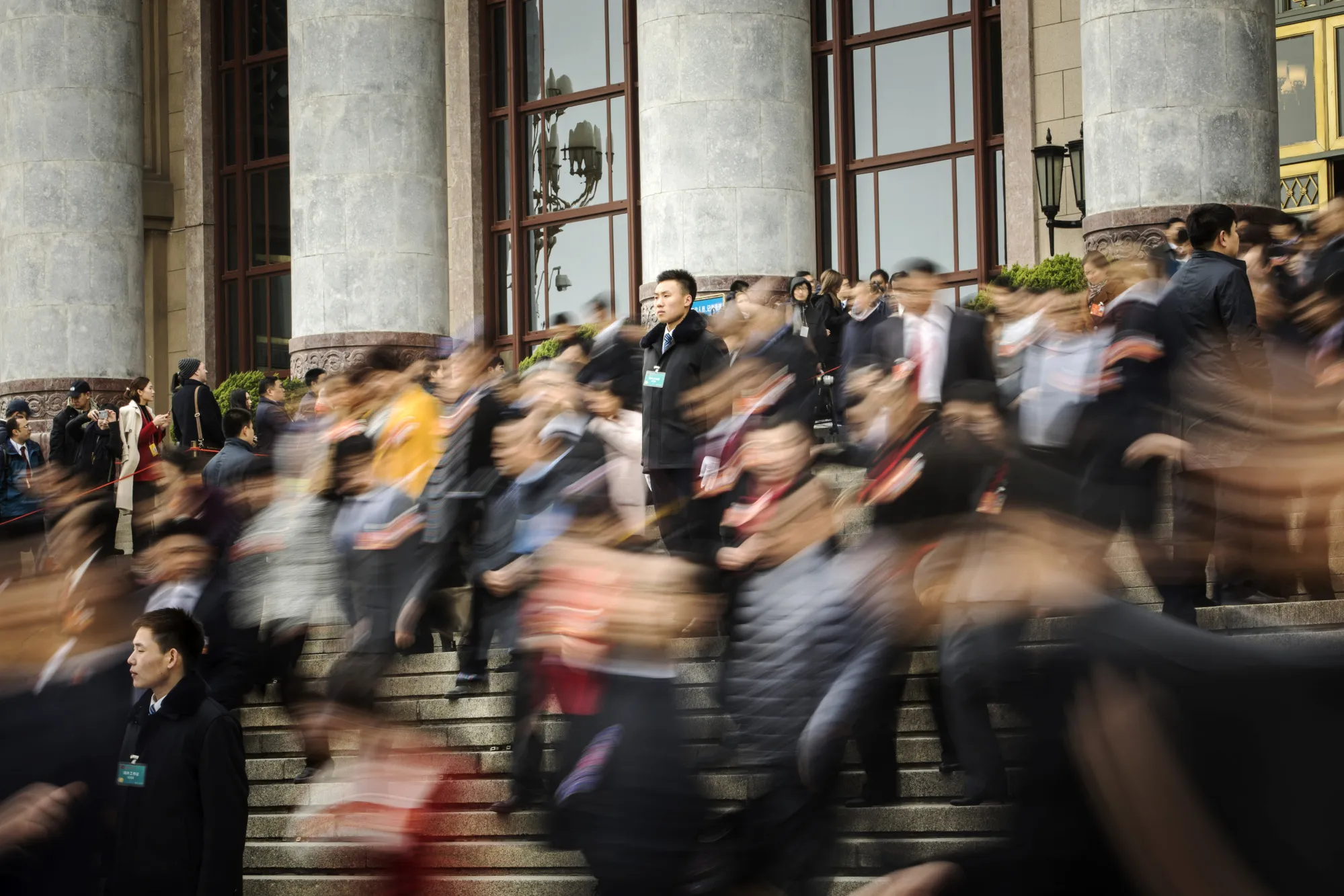 An attendant, center, stands as delegates leave the Great Hall of the People following a group session at the first session of the 13th Chinese People's Political Consultative Conference (CPPCC) in Beijing, on&nbsp;March 4.&nbsp;