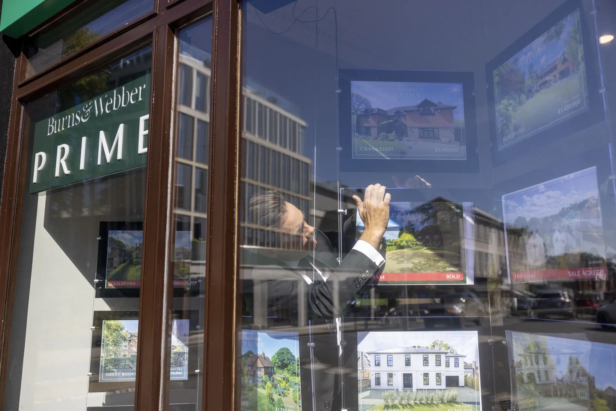 An employee removes an advertisement for a sold property from the window of an estate agent in Guildford.