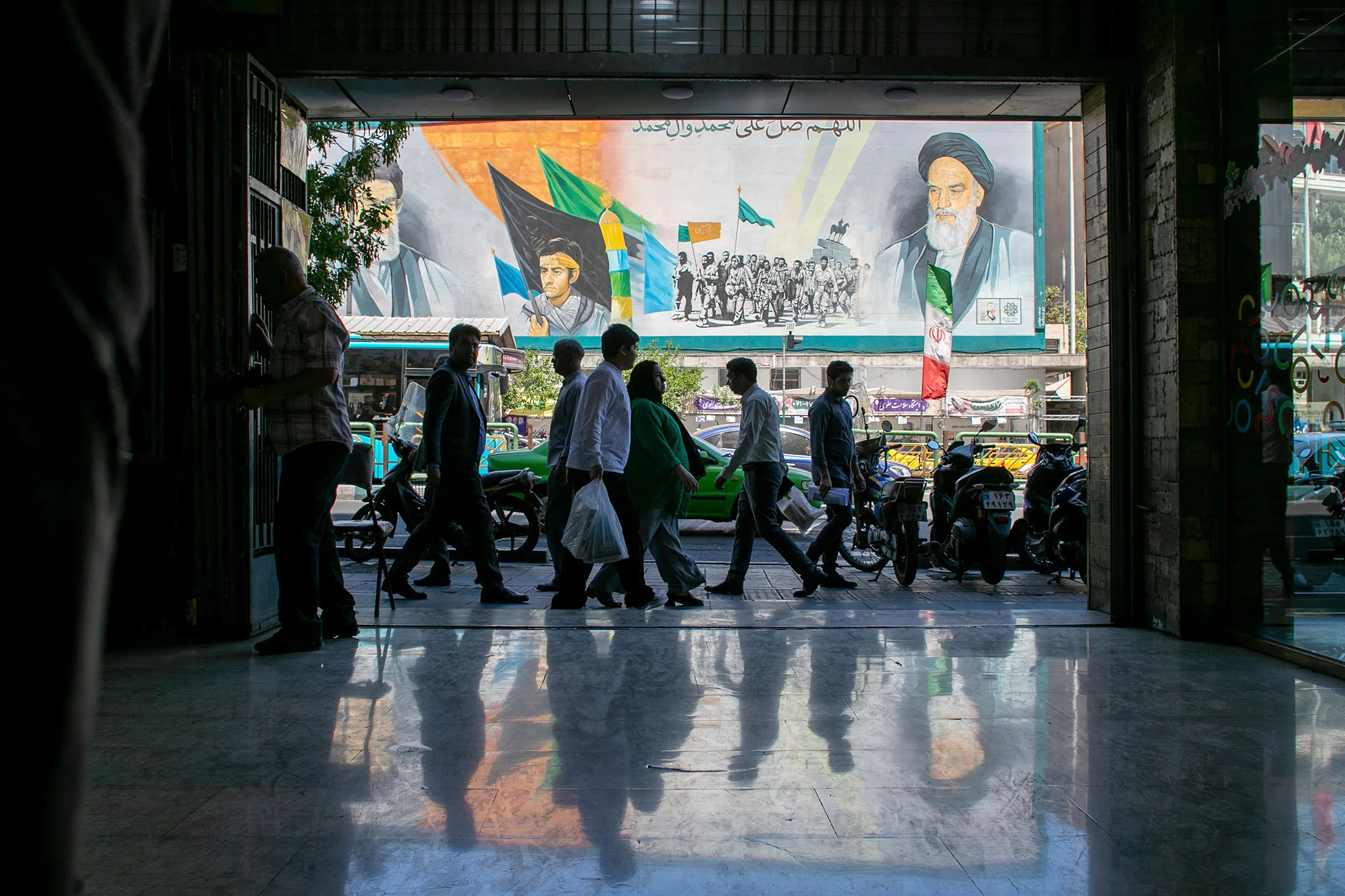 People pass a billboard depicting former Iranian supreme leaders in Tehran, on May 9.