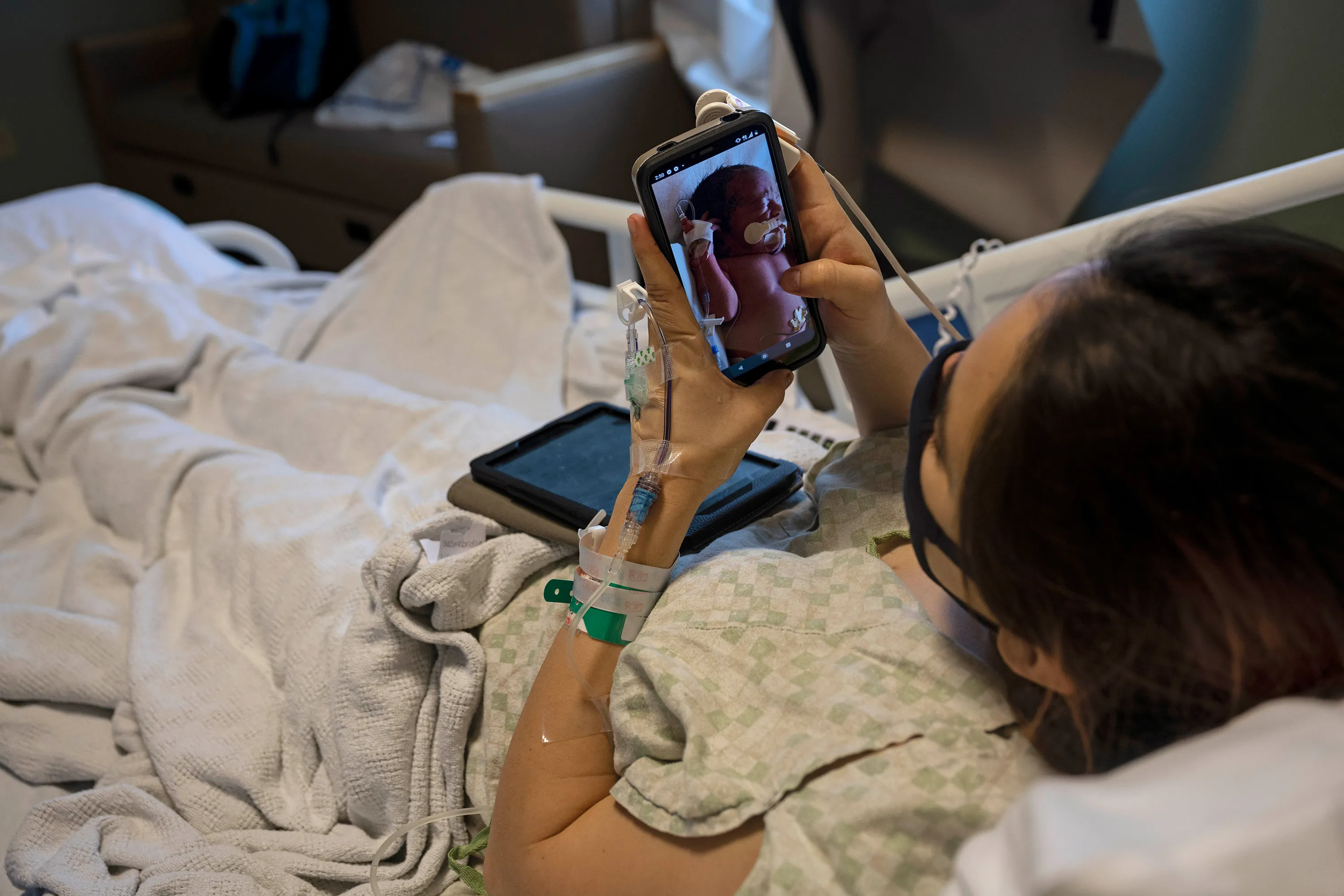 A mother, who tested positive for Coronavirus, looks at photographs of one of her babies sent to her by a nurse in a maternity ward in McAllen, Texas, U.S.