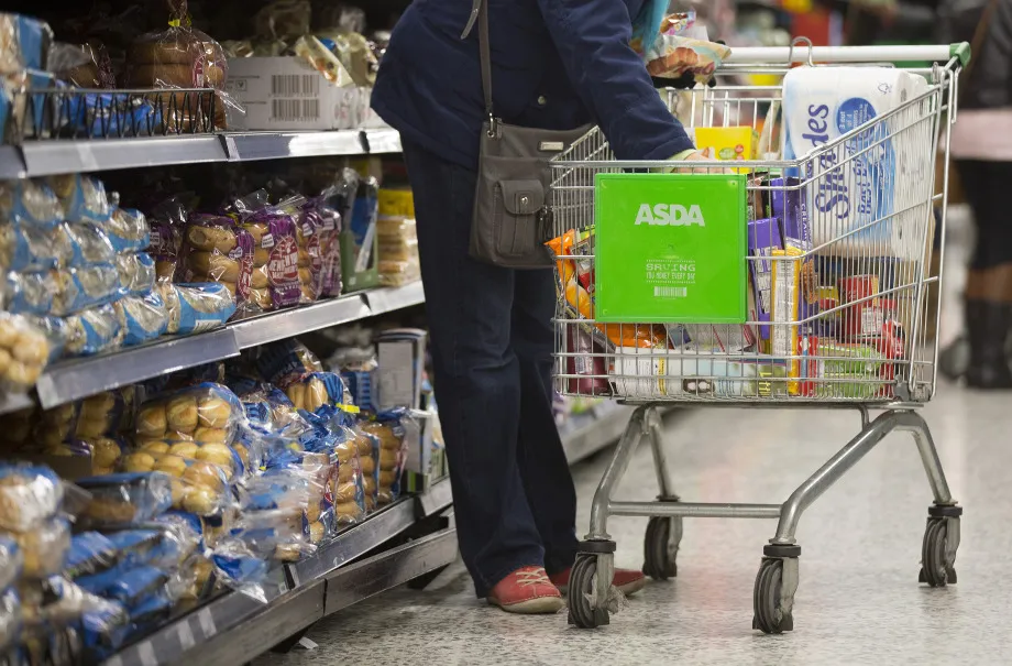A customer places items from a display of bread goods into her shopping cart inside an Asda supermarket, the U.K. retail arm of Wal-Mart Stores Inc., in Watford, U.K.