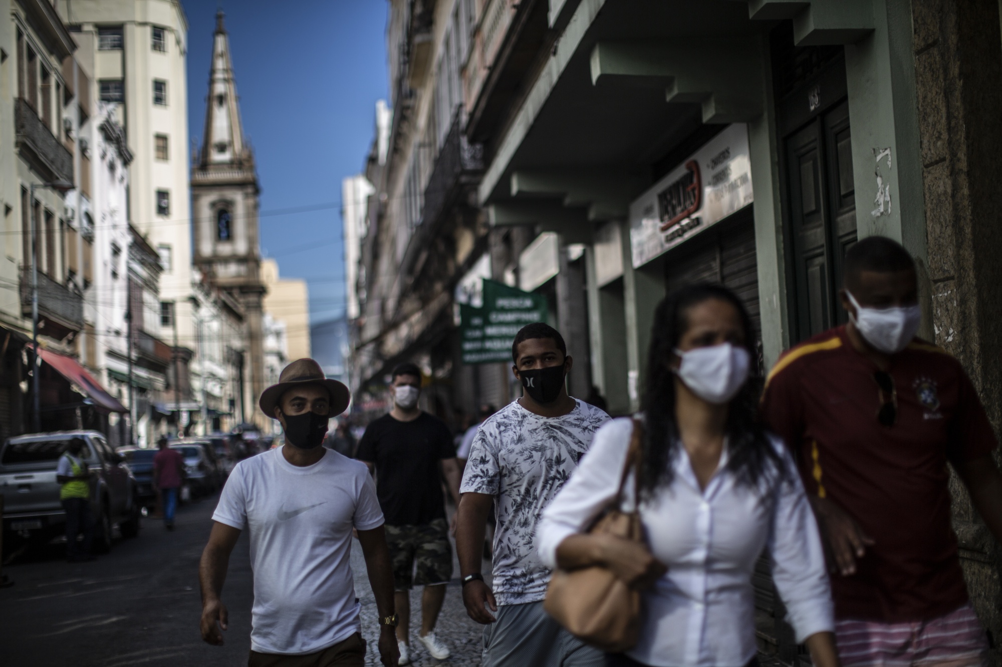 People wearing protective masks walk past partially opened businesses in downtown Rio de Janeiro, Brazil, on&nbsp;June 20.&nbsp;