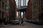 A pedestrian walks a dog along Front Street in New York.