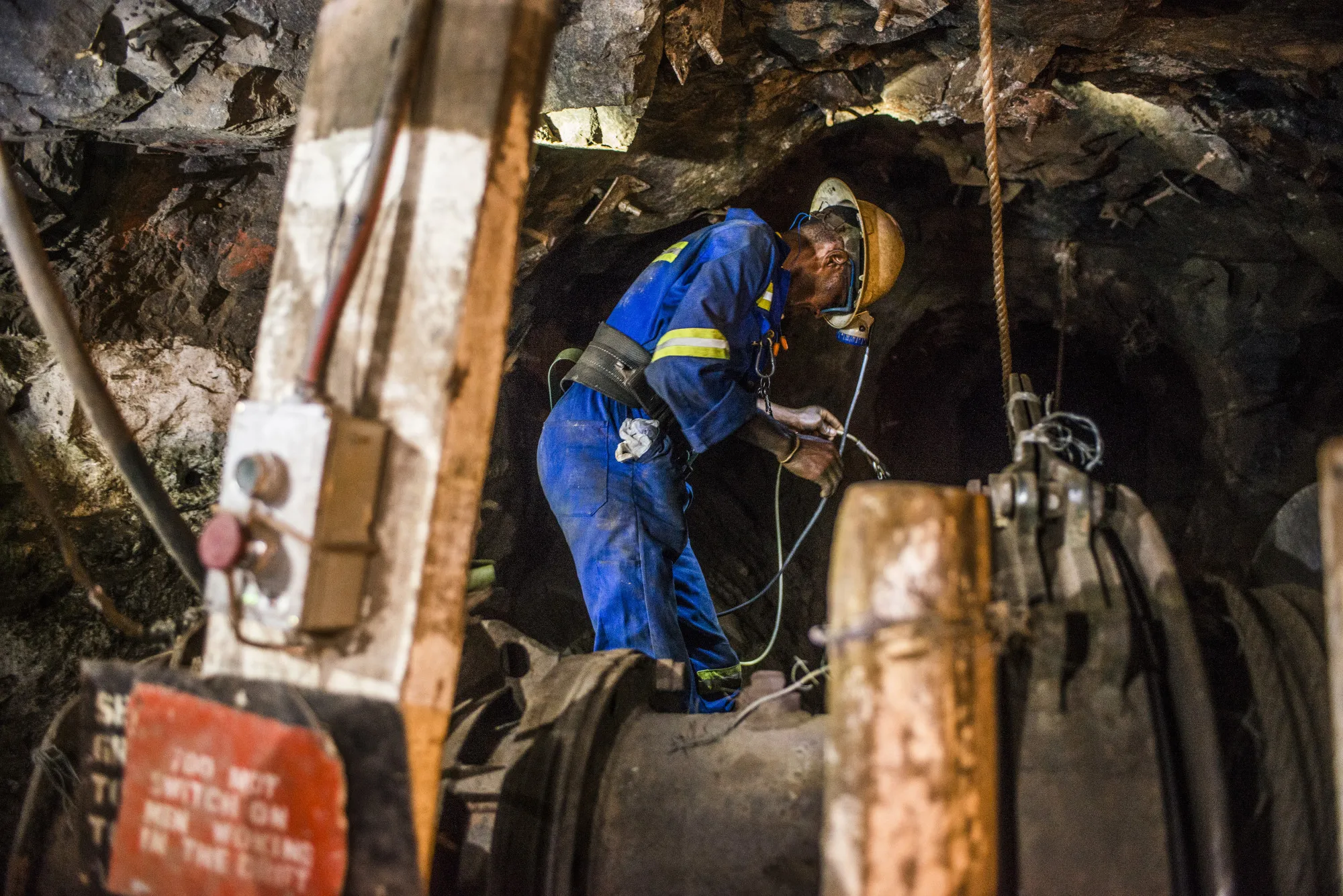 A miner checks equipment while mining for copper ore in an underground tunnel in a copper mine in Chingola, Zambia.