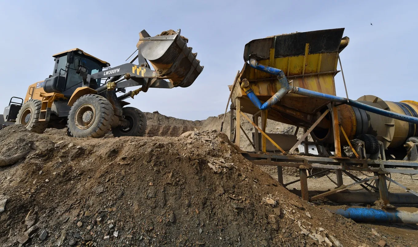 An excavator loads a mixture of sand and pebble containing gold particles into the dredge near the village of Soykechar, Uzbekistan.
