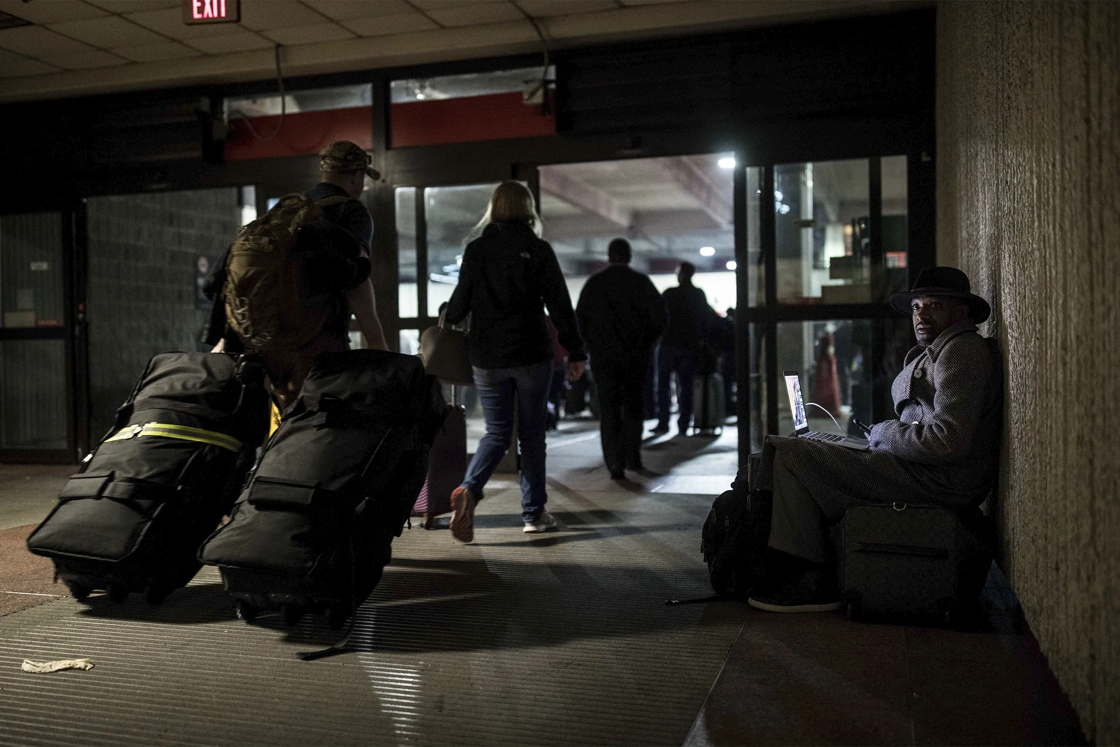 A traveler waits in dark at Hartfield-Jackson Atlanta International Airport, Sunday, Dec. 17, 2017, in Atlanta. A sudden power outage at the airport on Sunday grounded scores of flights and passengers during one of the busiest travel times of the year.