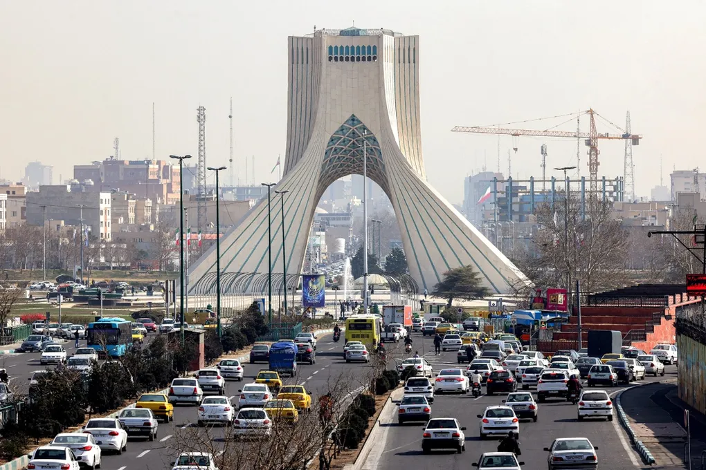نمایی از خودروها در حال حرکت در بزرگراهی نزدیک برج آزادی در تهران.