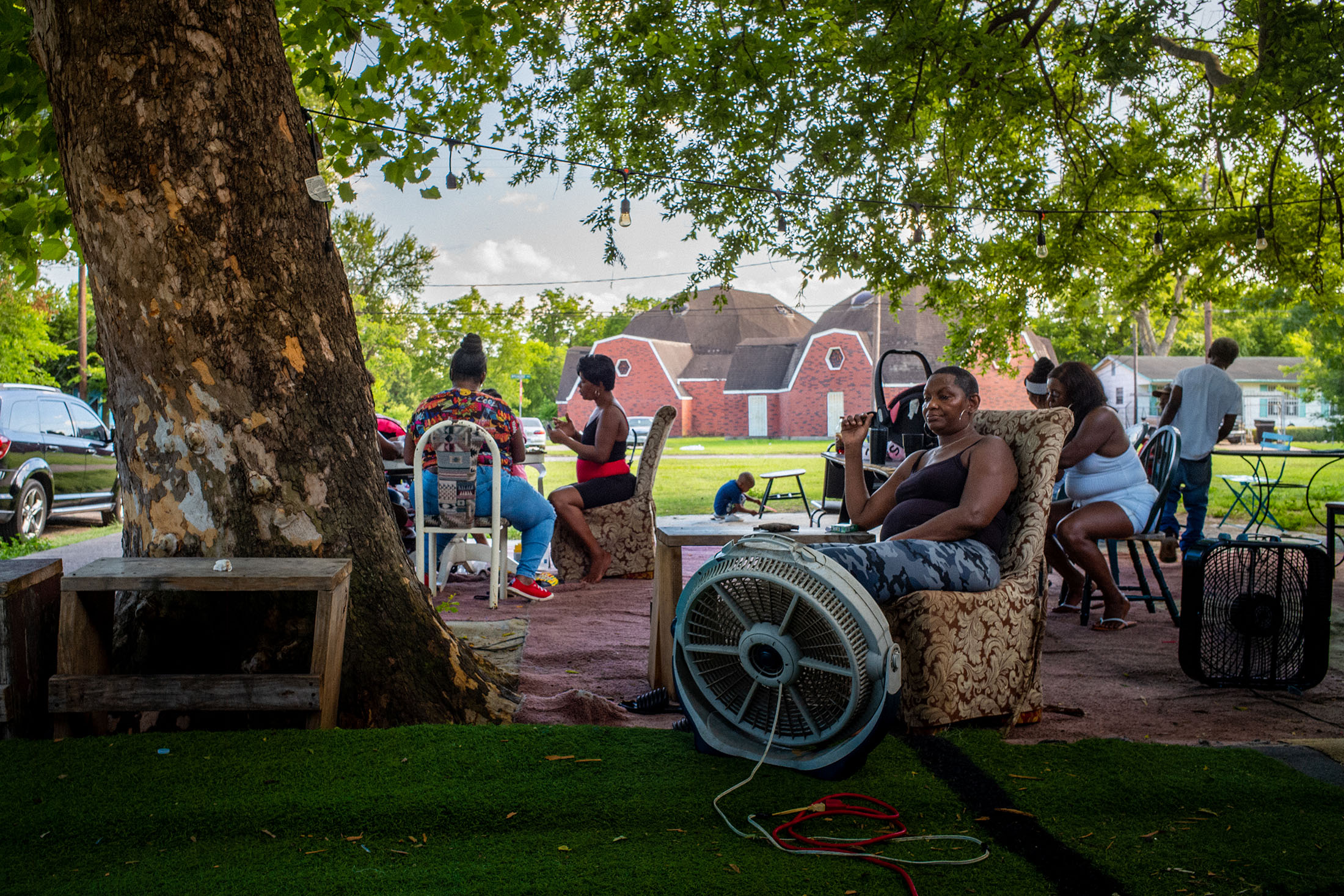 Resident sit in the shade with fans&nbsp;outside of a home in Houston, Texas,&nbsp;on June 10.