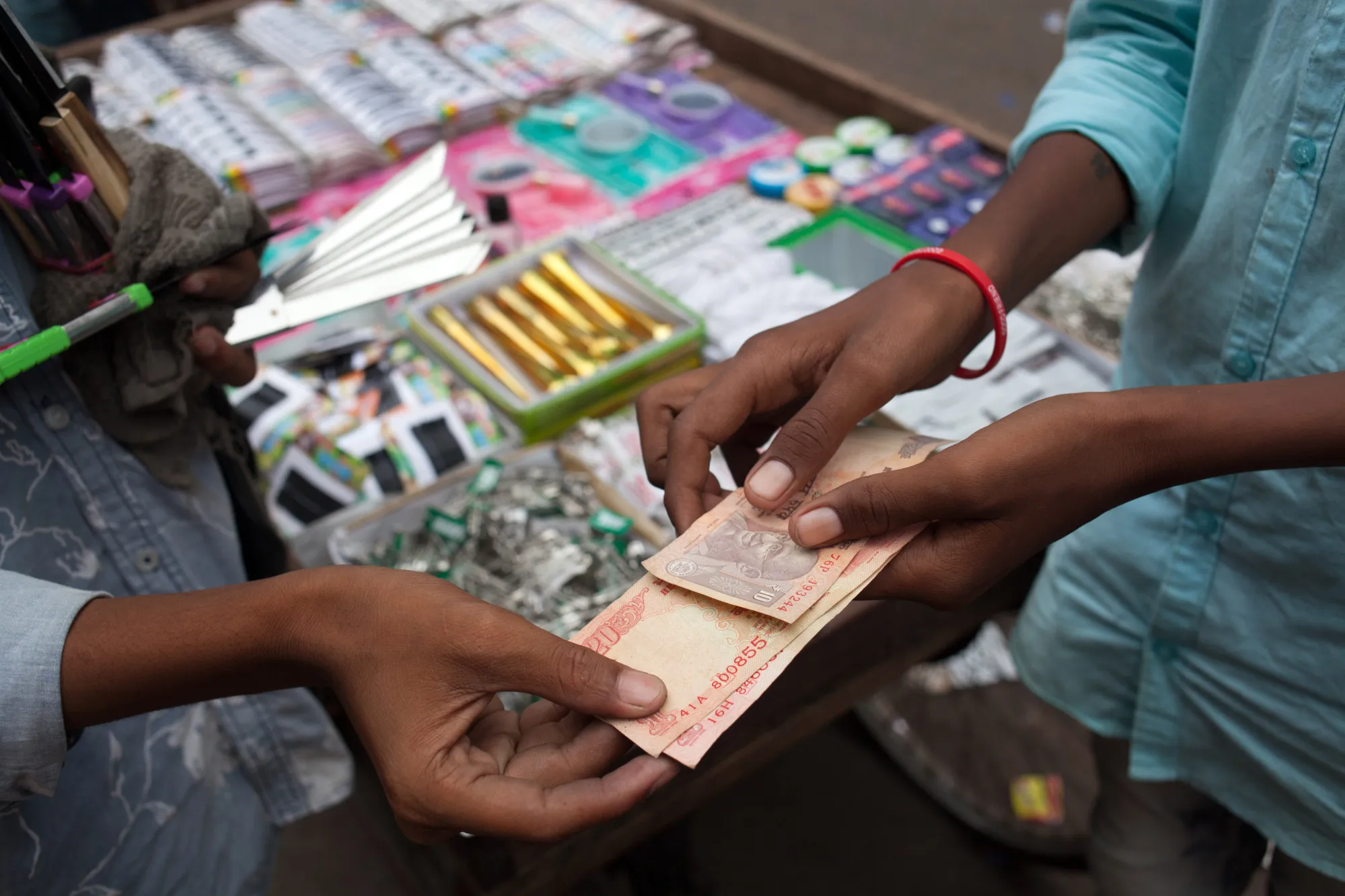 A vendor hands Indian rupee banknotes to a customer at a stall in Chauta Bazaar in Surat, Gujarat, India.