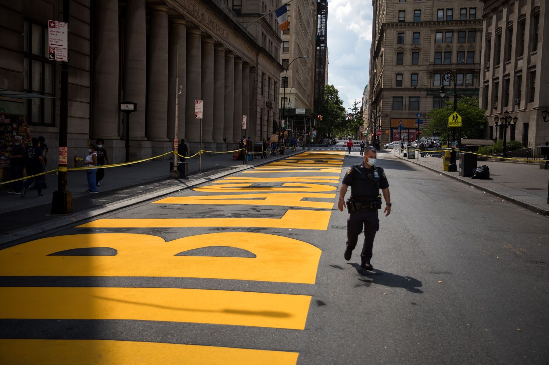 A New York City Police Department (NYPD) officer wearing a protective mask walks past the Black Lives Matter street mural on the road in front of Borough Hall in the Brooklyn borough of New York, U.S., on Friday, June 26, 2020. 