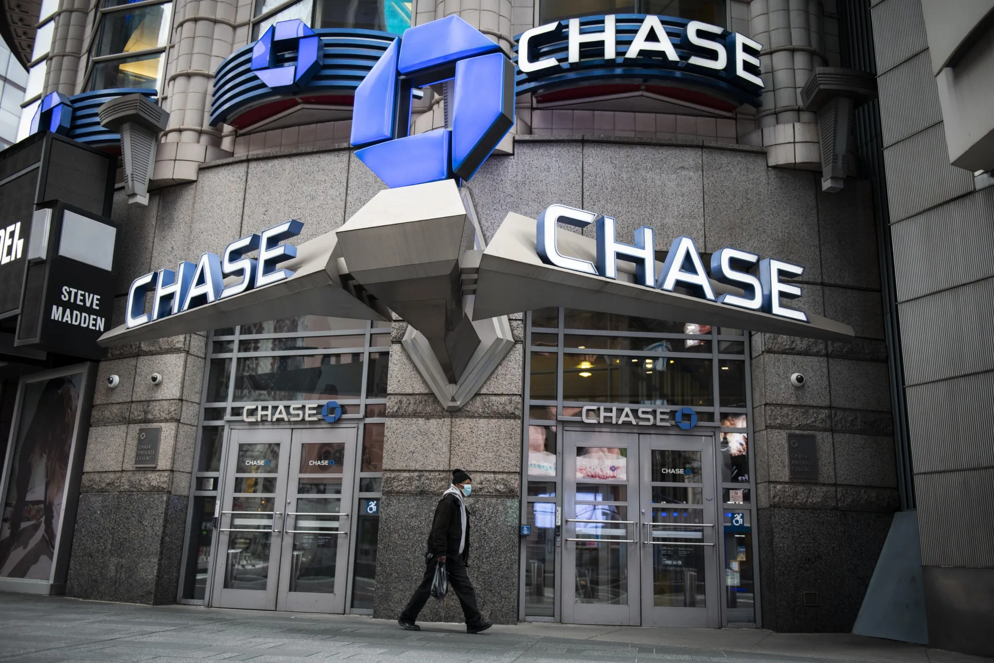 A pedestrian wearing a protective mask walks past a JPMorgan Chase &amp; Co. bank branch in New York, on April 10.
