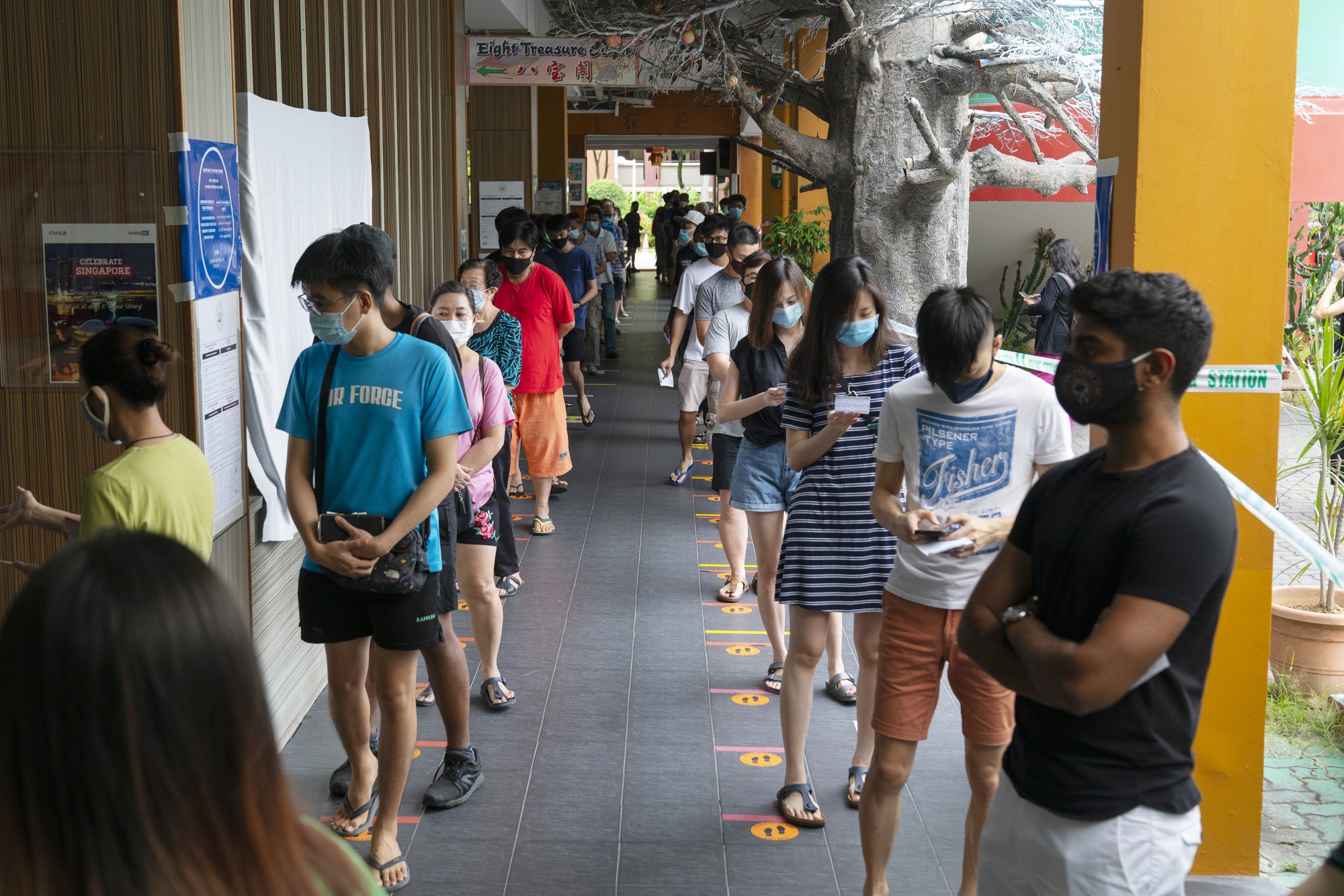 Voters wearing protective masks observe social distancing measures while waiting in line at the Poi Ching School polling station in Singapore, on July 10.