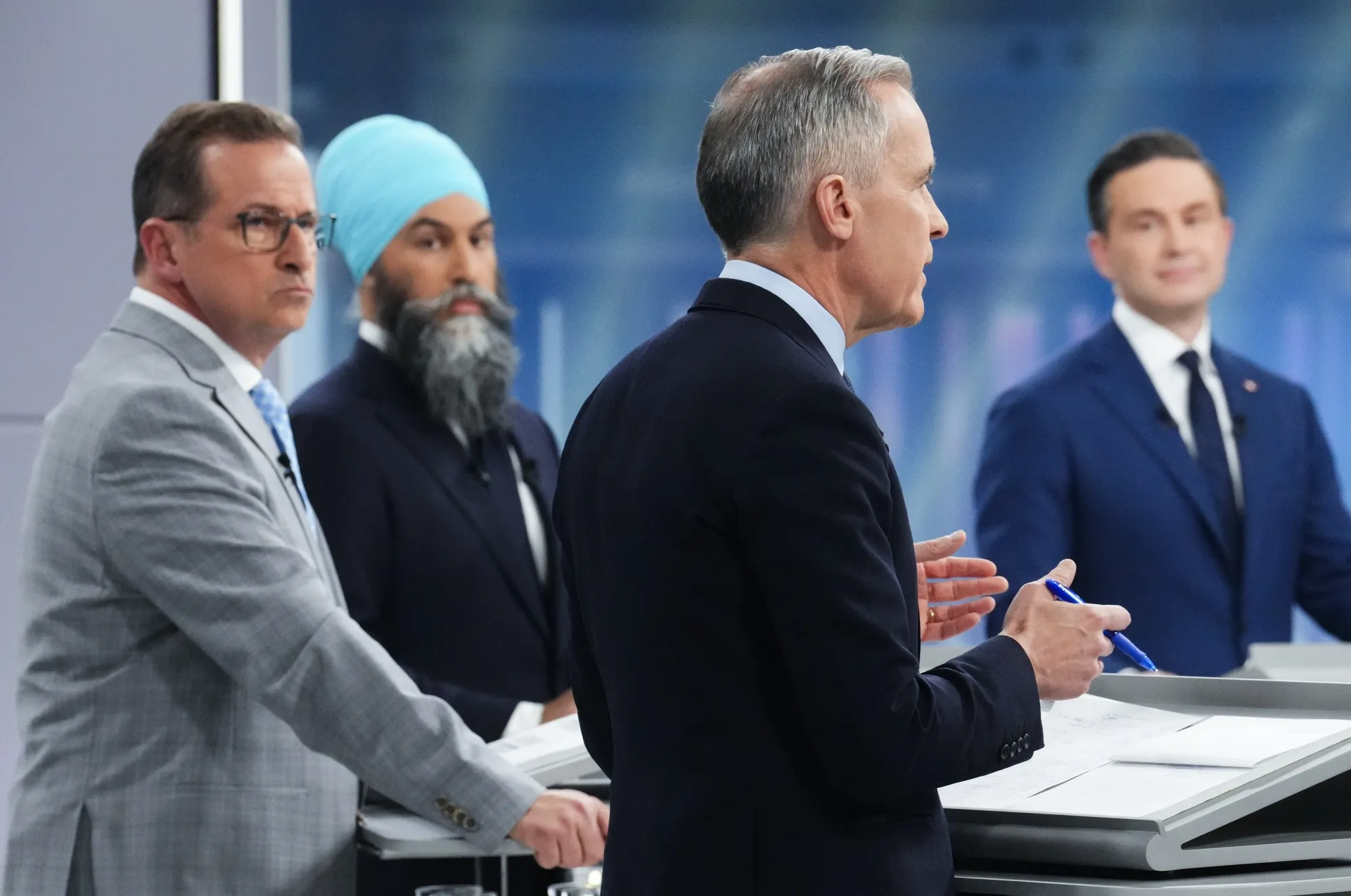 Mark Carney, Canada's prime minister and Liberal Party leader, foreground, speaks as Pierre Poilievre, Conservative Party leader, on right, listens at an election debate. Bloc Quebecois Leader Yves-Francois Blanchet and New Democratic Party Leader Jagmeet Singh are also pictured.