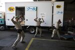 Yamato Transport Co. drivers stretch in front of a delivery truck before departing a Yamato branch in Musashimurayama, Tokyo, Japan.