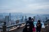 People wearing protective masks stand on a viewing terrace at Victoria Peak in Hong Kong, China, on Monday, Feb. 3, 2020. The outlook for the Hong Kong economy in 2020 is “subject to high uncertainties” including the global economic recovery, U.S.-China trade relations, the ongoing protests and the progression of the viral outbreak, the government said in a release.