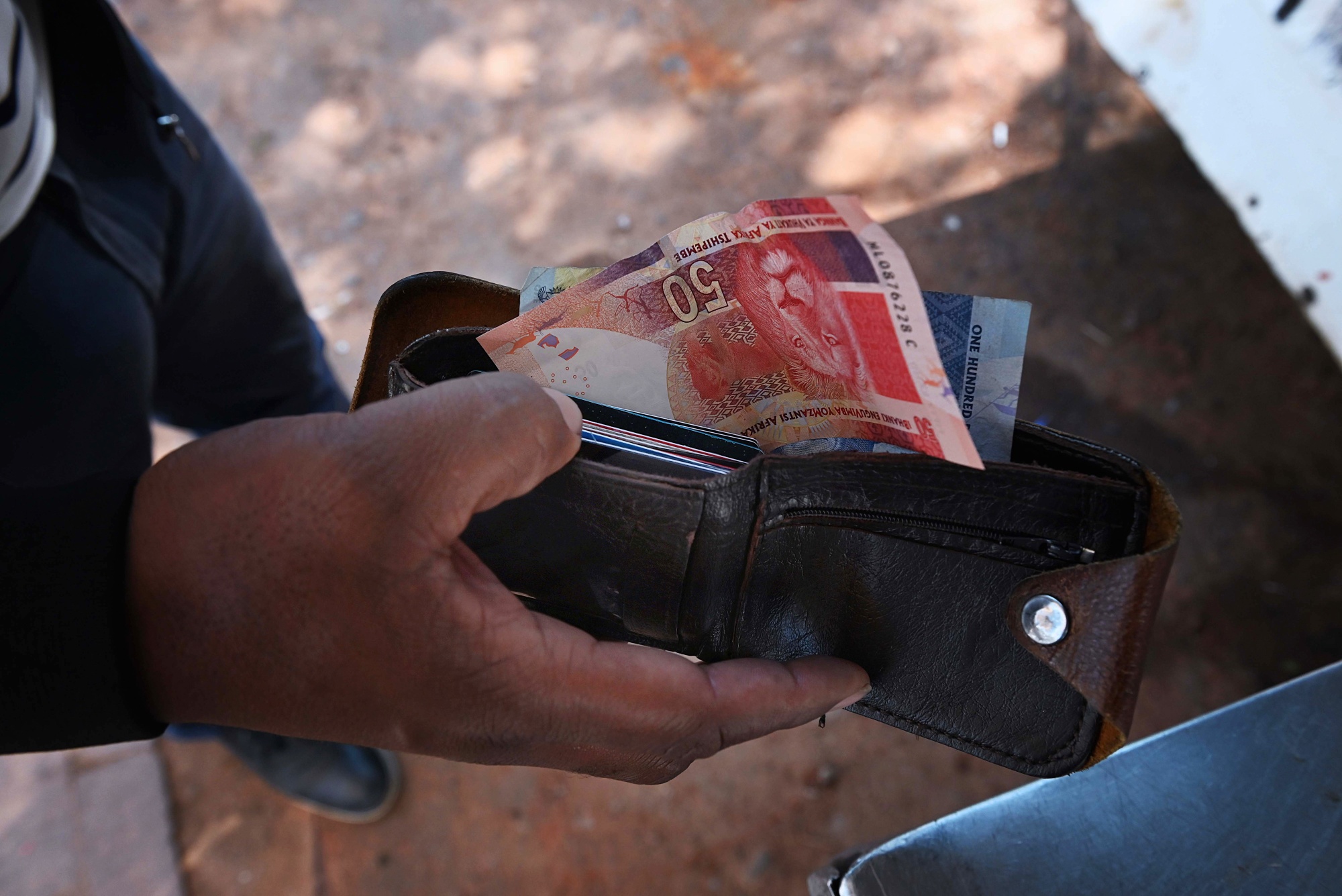 A customer with South African rand banknotes at a street vendor's stall in the Sandton district of Johannesburg, South Africa.