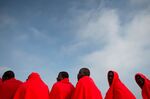 A group of migrants warm up with Red Cross blankets on board a Spanish coast guard vessel as they arrive at Malaga's harbour.