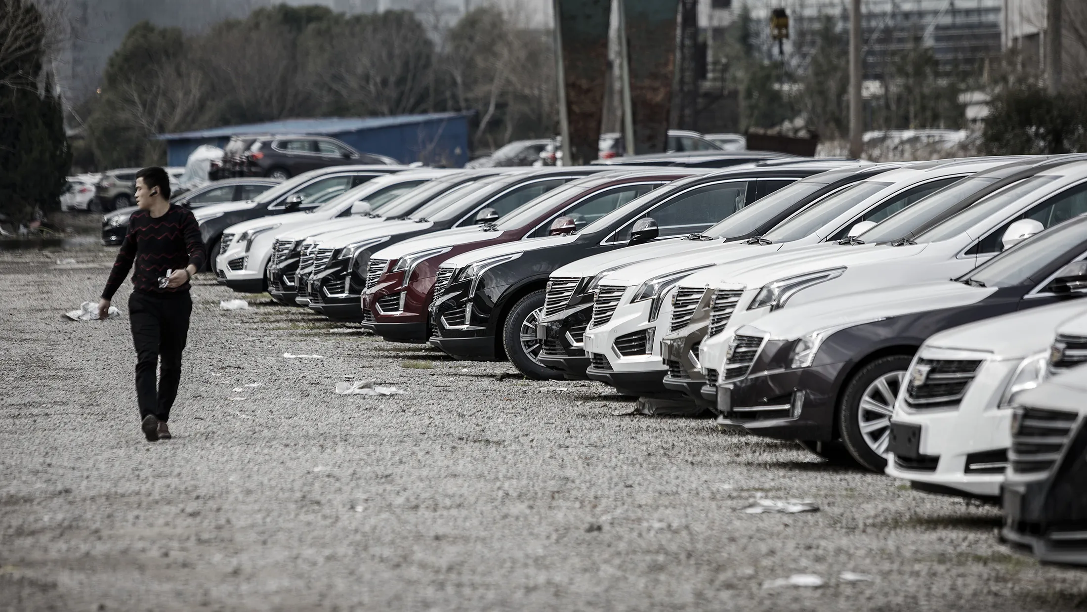 A man walks past new cars parked at a General Motors Co. (GM) Cadillac dealership in Shanghai, China, on Monday, Jan. 16, 2017. Cadillac sees 'tremendous opportunities' in third and fourth-tier cities in China, according to Andreas Schaaf, vice president of Cadillac China.

