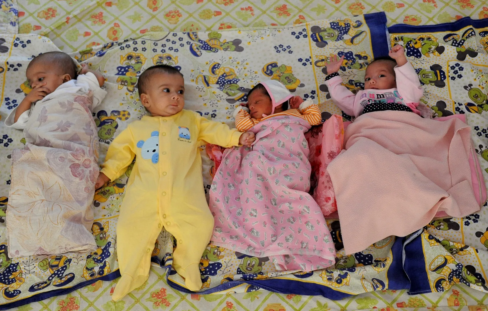 Orphaned Indian baby girls lie on a blan