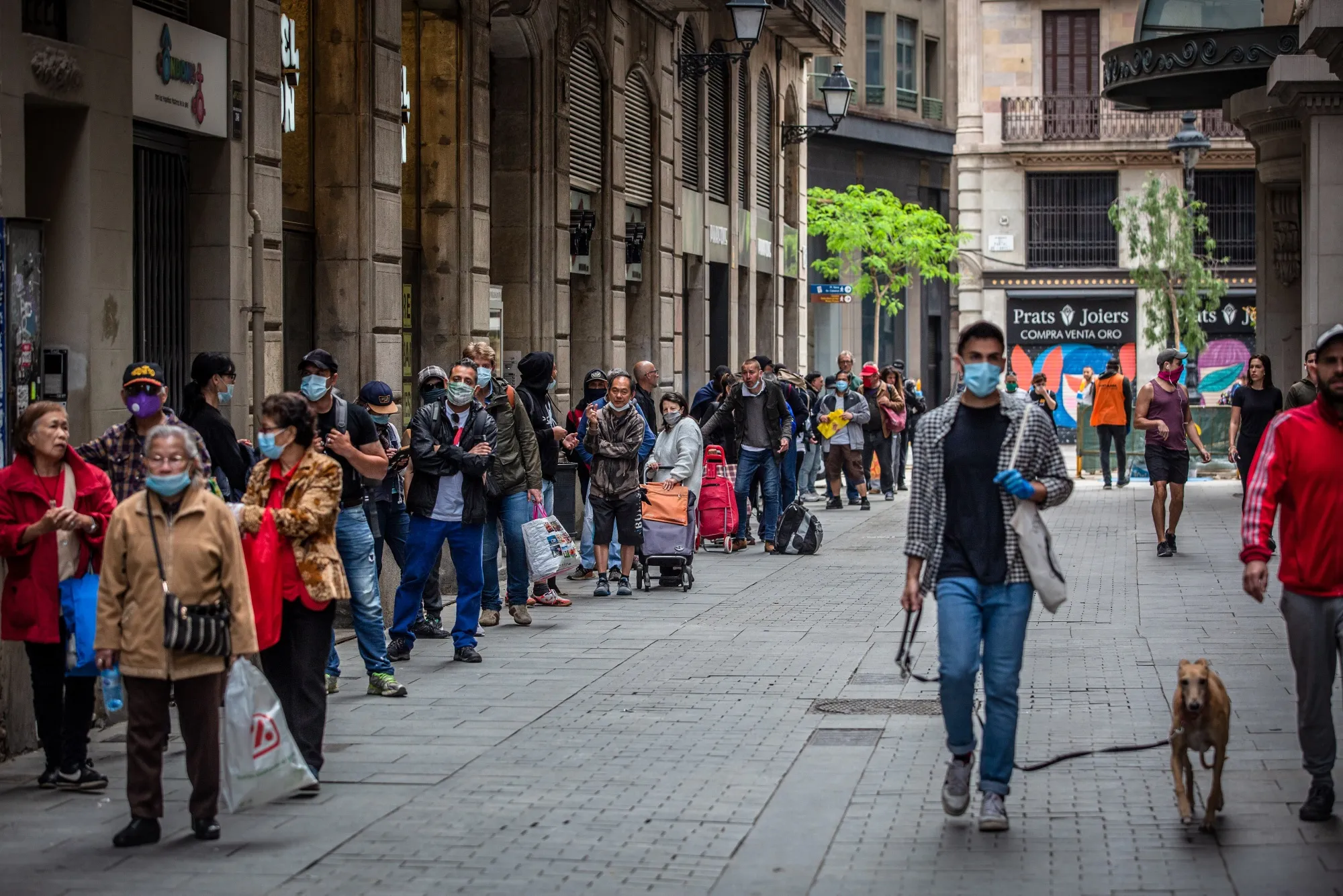 People queue along the street to collect food aid from a distribution point at the Santa Anna church in Barcelona, on May 17.