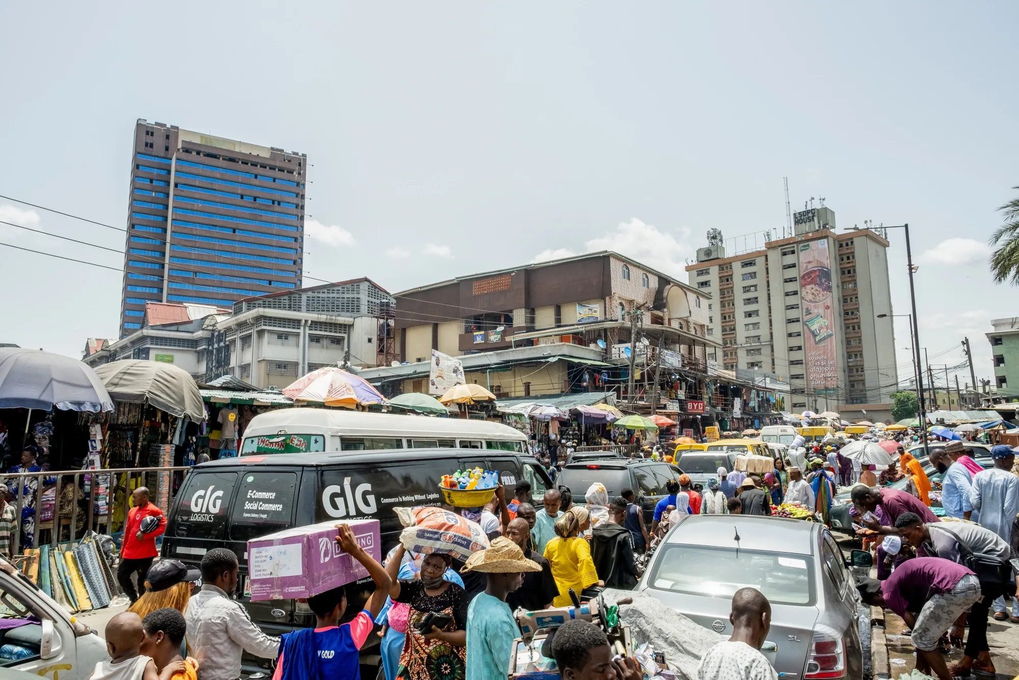 Traders and pedestrians move between heavy traffic in a market area of Lagos, Nigeria.