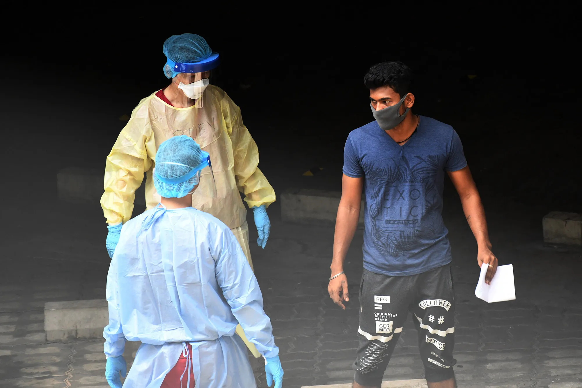 Healthcare staff talk to a migrant worker at a foreign workers' dormitory&nbsp;in Singapore.