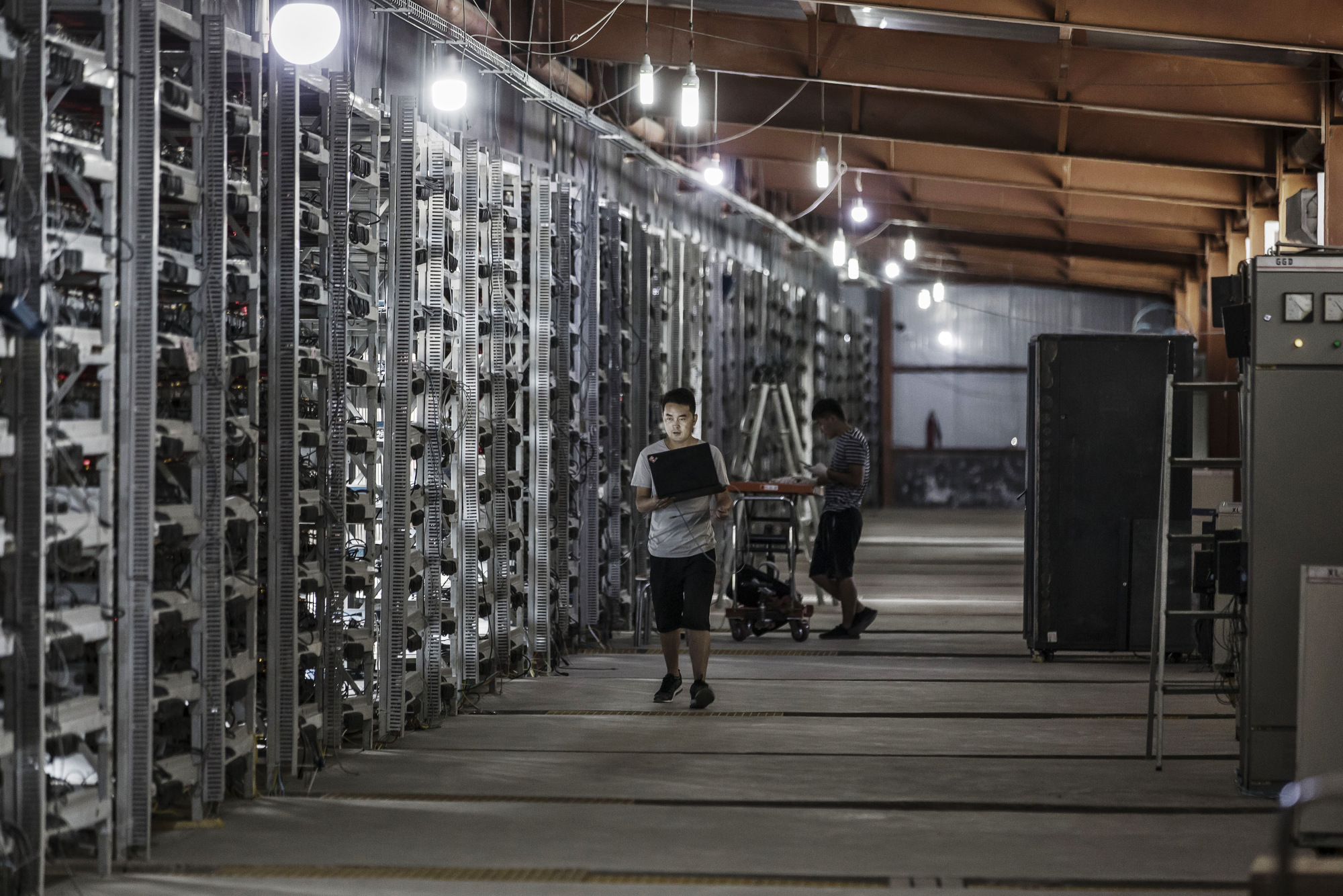 Technicians inspect bitcoin mining machines.