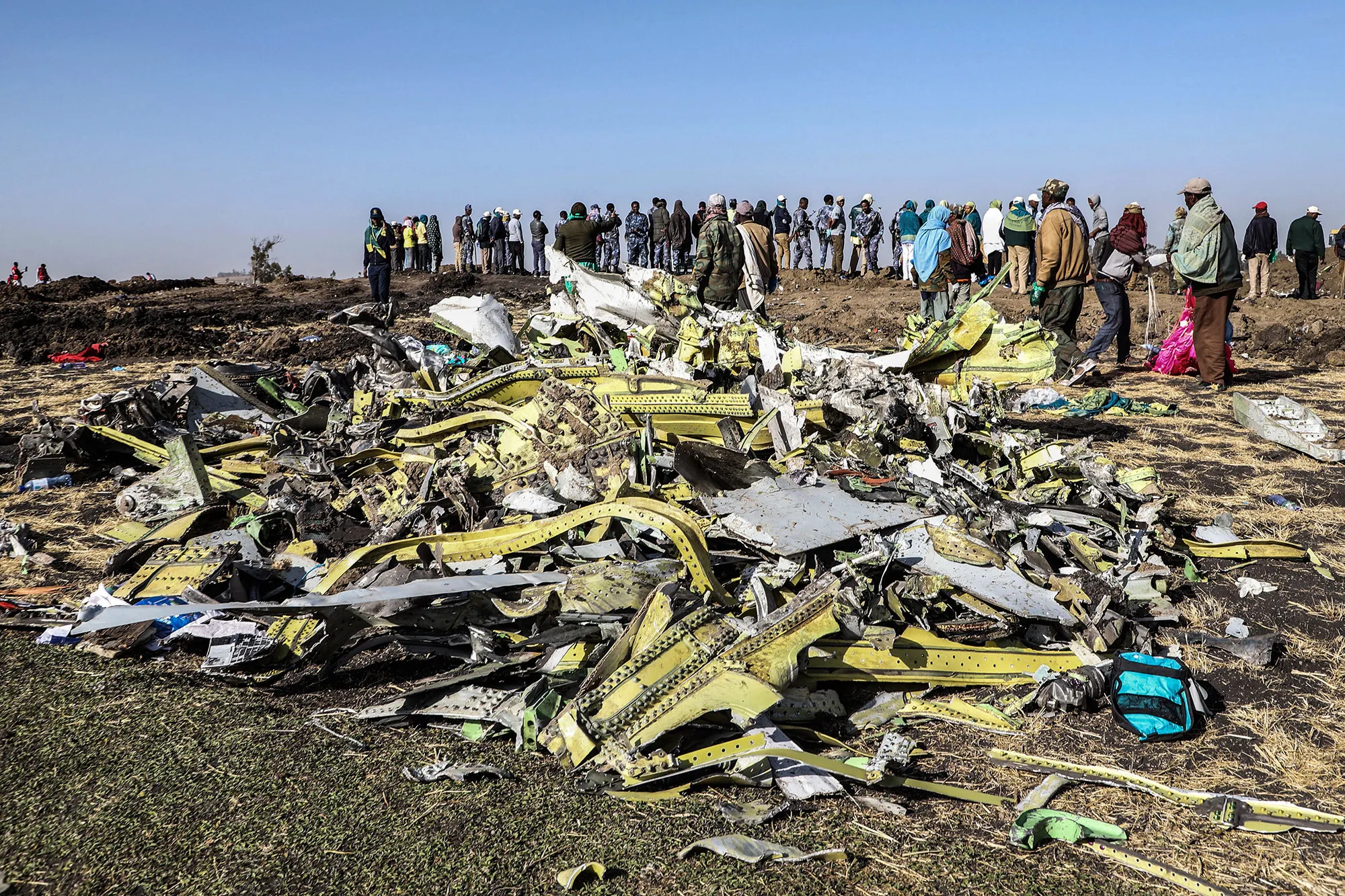 People stand near collected debris at the crash site of Ethiopia Airlines near Bishoftu, in 2019