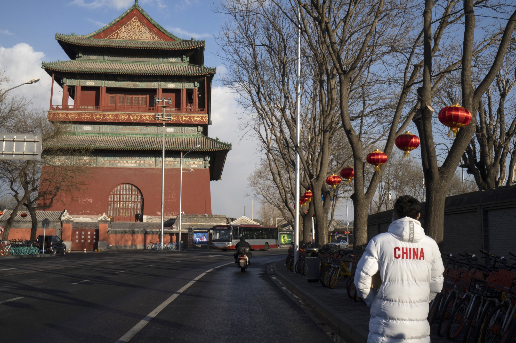 A pedestrian walks along a road past the Drum Tower in Beijing.