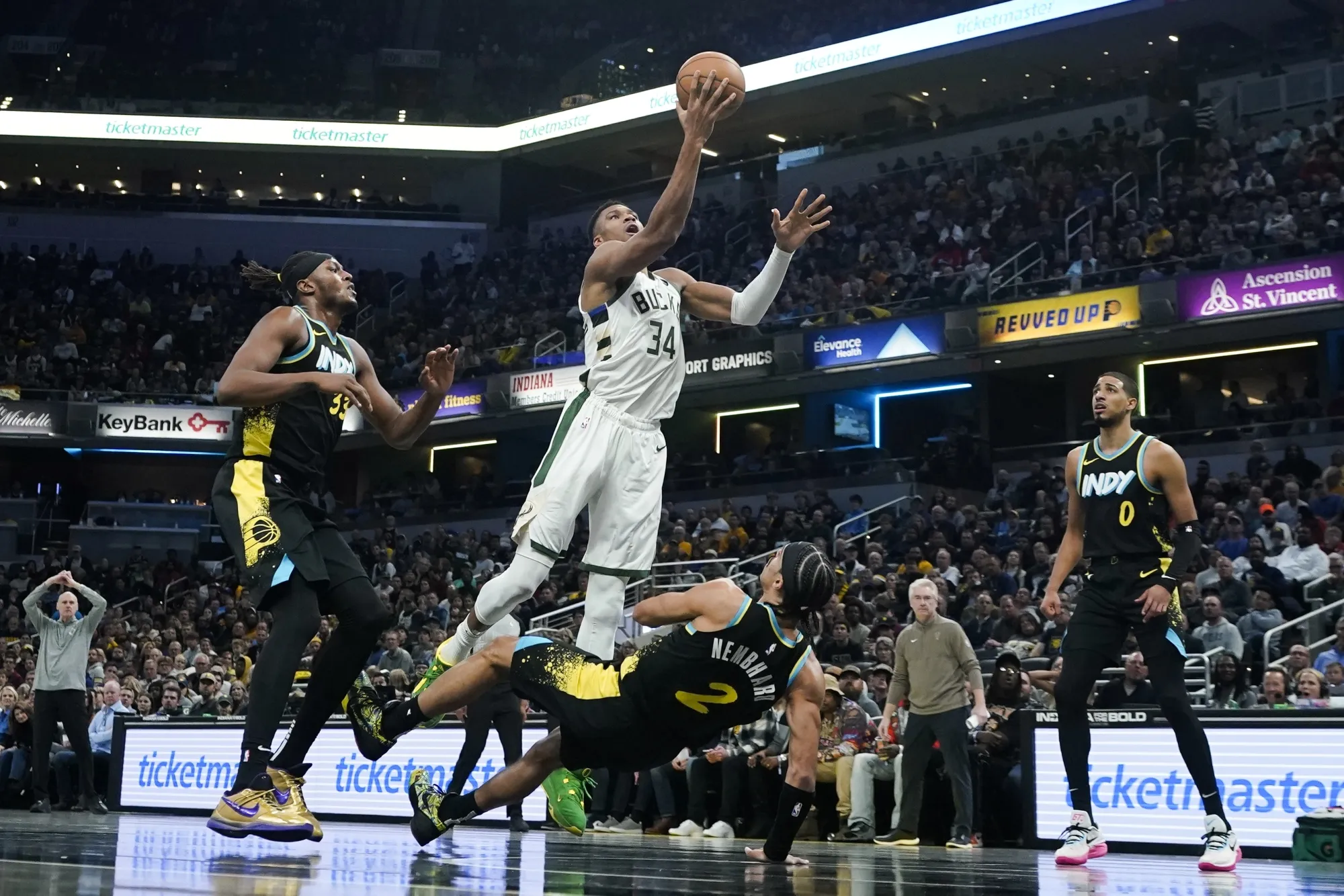 Indiana Pacers' Andrew Nembhard (2) defends asMilwaukee Bucks' Giannis Antetokounmpo (34) goes up for the basket during the second half of an NBA basketball game, Thursday, Nov. 9, 2023, in Indianapolis. Nembhard was called for a blocking foul on the play. (AP Photo/Darron Cummings)