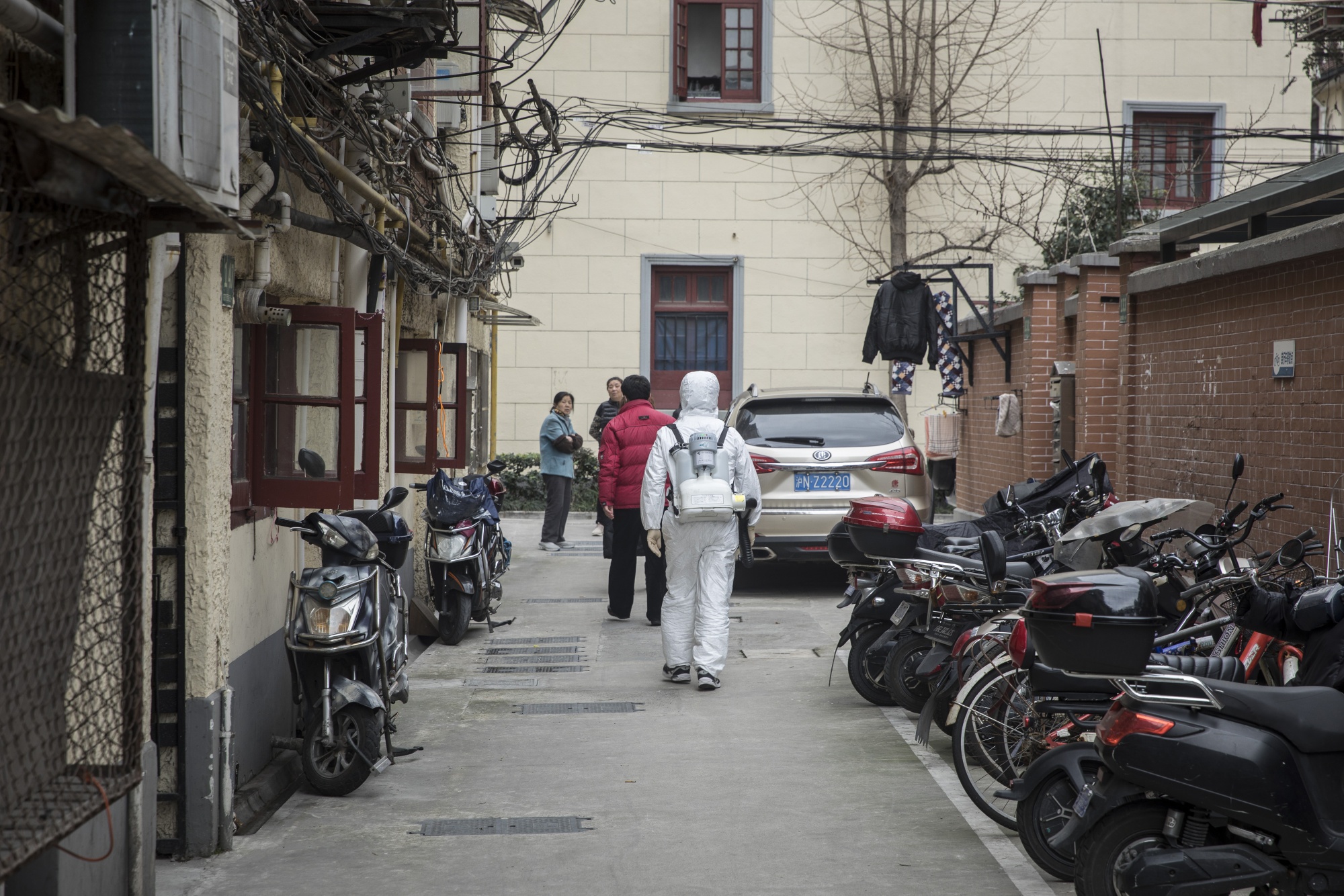 A man wearing a protective suit and carrying a backpack of disinfectant walks through a neighborhood in Shanghai on Feb. 5.