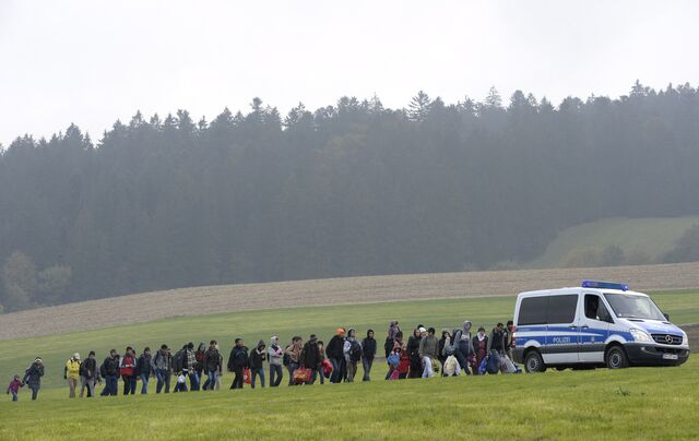 Migrants walk behind a police car during their way from the Austrian-German border to a first registration hall of the German federal police in the small Bavarian village Wegscheid, southern Germany, on October 20, 2015.