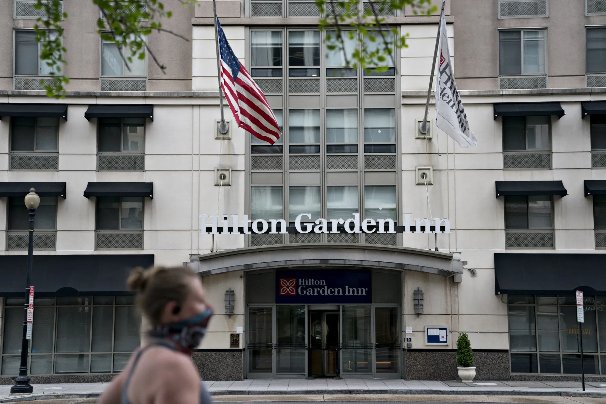 A runner wearing a protective mask passes the Hilton Garden Inn hotel in Washington, D.C. on April 23.&nbsp;
