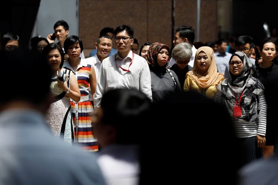 Office workers cross a street during lunch hour in the central business district in Singapore.