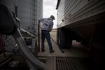 A worker sweeps after unloading corn from a grain truck in Princeton, Illinois.