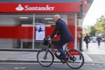 An office worker using a Santander Cycle hire bike travels passes a Banco Santander SA bank branch in London, U.K., on Friday, Oct. 22, 2021. 