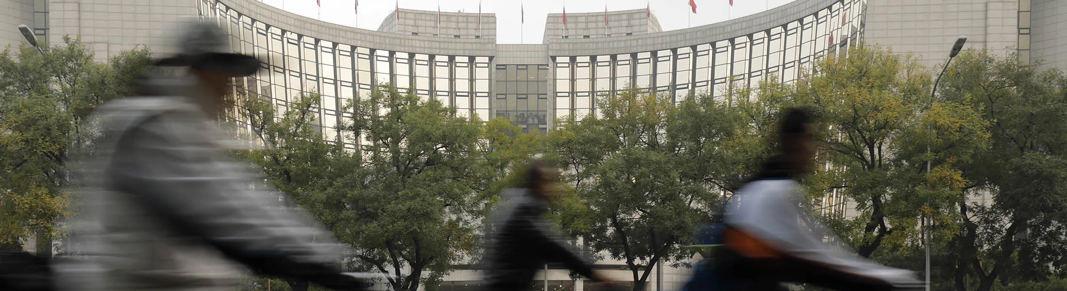 Cyclists ride past the People's Bank of China headquarters in Beijing, China, on Thursday, Oct. 19, 2017. Chinese President Xi Jinping has quietly dropped a commitment made by his predecessor to double the size of his nation's economy.
