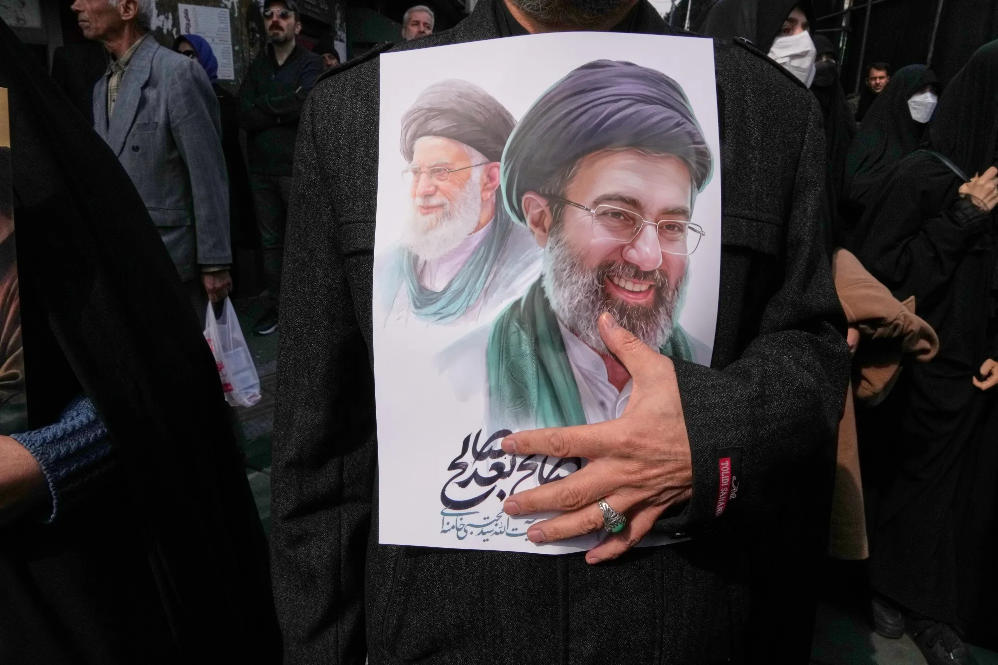 A man holds a poster of Iran’s Supreme Leader Mojtaba Khamenei, right, and the late Ayatollah Ali Khamenei, in Tehran, on March 11.