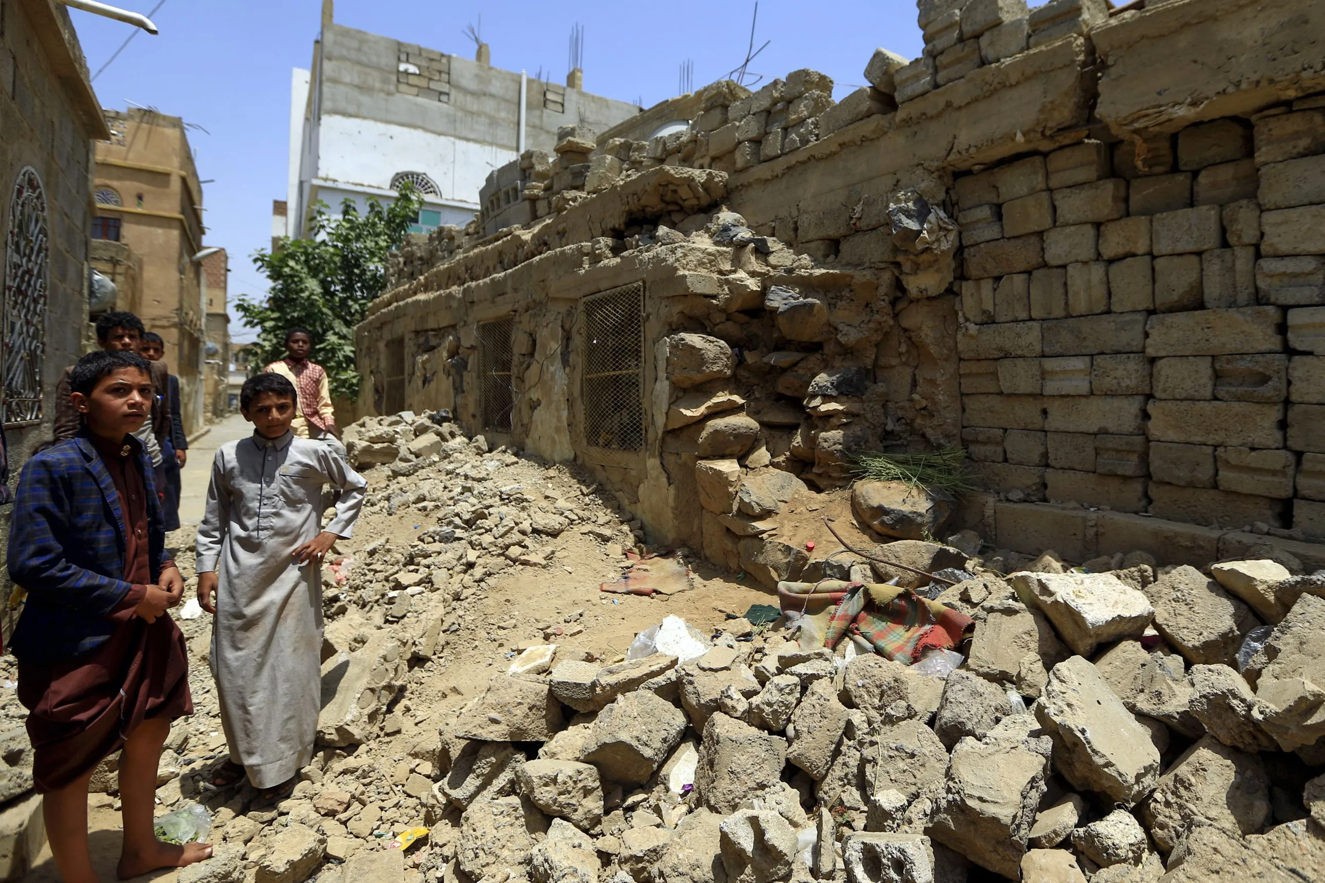 People stand amidst the ruins of a building destroyed during past Saudi-led coalition air strikes&nbsp;in the province of Amran on July 6.