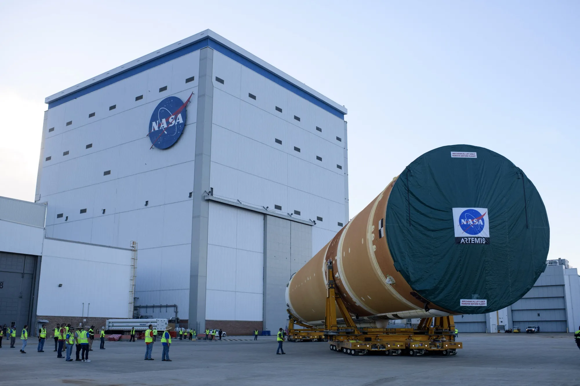 NASA employees watch as the Artemis II rocket core stage is wheeled out at the NASA Michoud Assembly Facility in New Orleans.&nbsp;