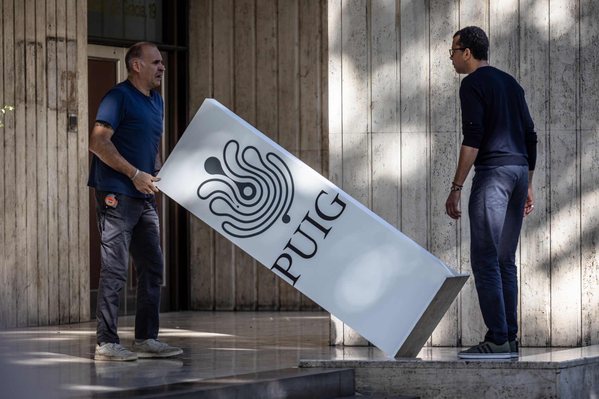 Workers prepare branding for the Puig Brands SA listing ceremony at the Barcelona Stock Exchange in Barcelona, Spain, on Friday, May 3, 2024. Spanish beauty and fragrance group Puig and its founding family raised €2.6 billion ($2.8 billion), pricing shares at the top end of the marketed range in Europe's biggest listing so far this year. Photographer: Angel Garcia/Bloomberg